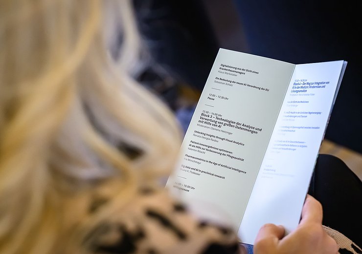 Woman in the audience holding a program — Picture: MedUni Wien / Marko Kovic
