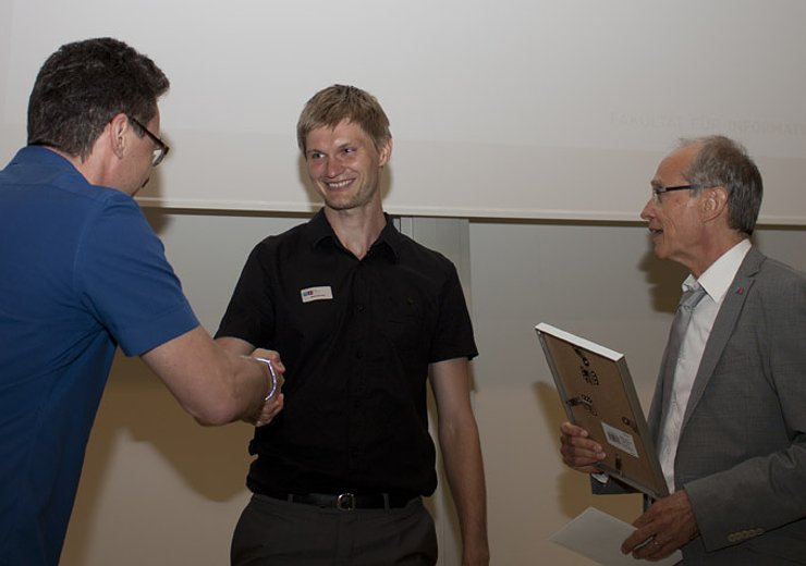 Andreas Steininger, Vorsitzender der Jury, und Dekan Gerald Steinhardt überreichen Matej Nezveda den Best Poster-Award. — Picture: TU Wien Informatics